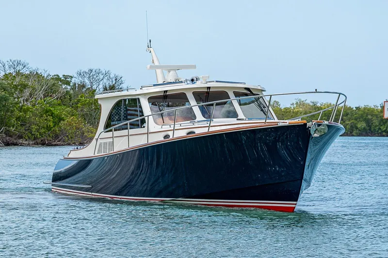 Slide: The Image of 2021 Hinckley Talaria 43 yacht cruising on calm waters near lush greenery. - 8