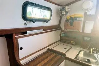Slide: The Image of 1987 Morris Linda boat interior with wooden cabinetry, sink, and fan. - 31
