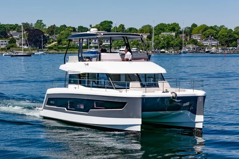 Slide: The Image of 2024 Fountaine Pajot MY5 yacht cruising on a serene lake with lush shoreline. - 1
