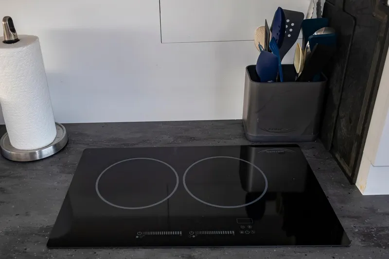 Slide: The Image of Modern kitchen countertop with induction cooktop, utensils, and paper towel holder on Fountaine Pajot MY5. - 58