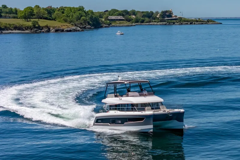 Slide: The Image of 2024 Fountaine Pajot MY5 yacht cruising on a serene blue sea near a lush coastline. - 59