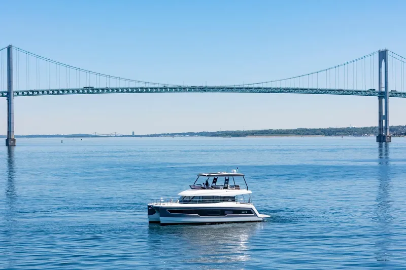 Slide: The Image of 2024 Fountaine Pajot MY5 yacht cruising under a large suspension bridge on a sunny day. - 63