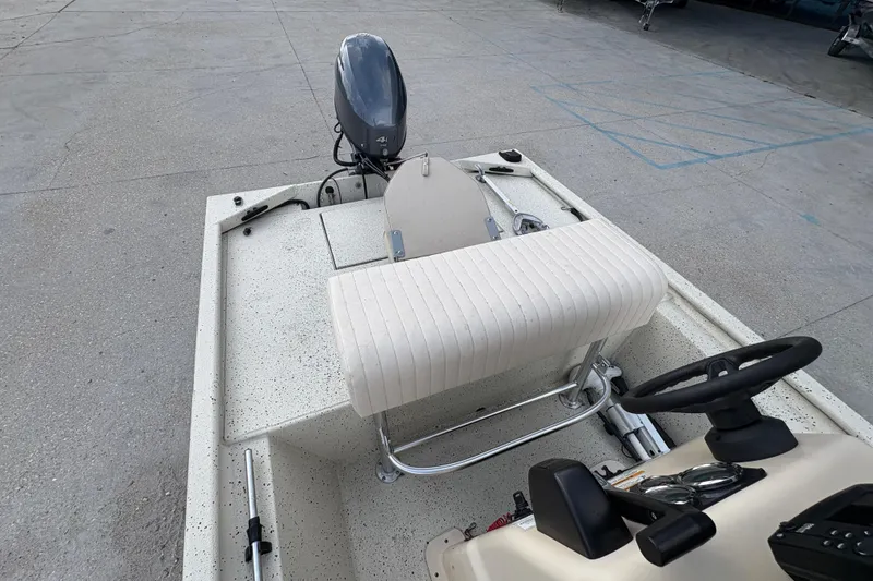 Slide: The Image of 2012 Xpress 1650VJF boat interior with steering wheel and motor, parked on concrete. - 14