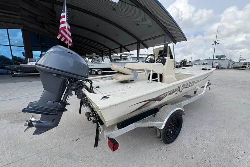Slide: The Image of 2012 Xpress 1650VJF boat with outboard motor, parked under a large canopy. - 3