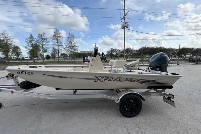Slide: The Image of 2012 Xpress 1650VJF boat on trailer, parked outdoors under a cloudy sky. - 6