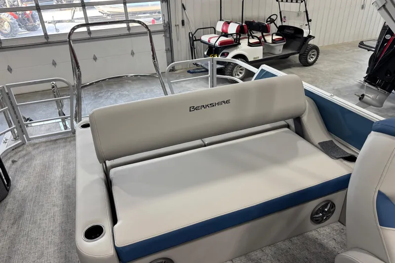 Slide: The Image of 2026 Berkshire 24 UL RE pontoon boat interior with plush seating in a garage setting. - 10