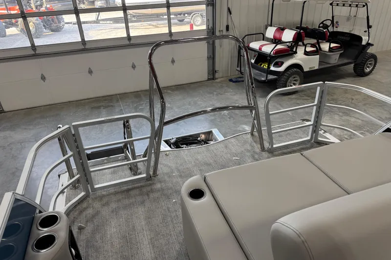 Slide: The Image of 2026 Berkshire 24 UL RE pontoon boat interior with seating and cup holders in a garage. - 9