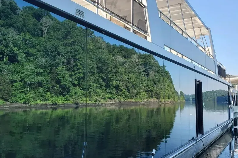 Slide: The Image of 2012 Thoroughbred Houseboat 21x103 reflecting lush green trees on a calm river. - 10