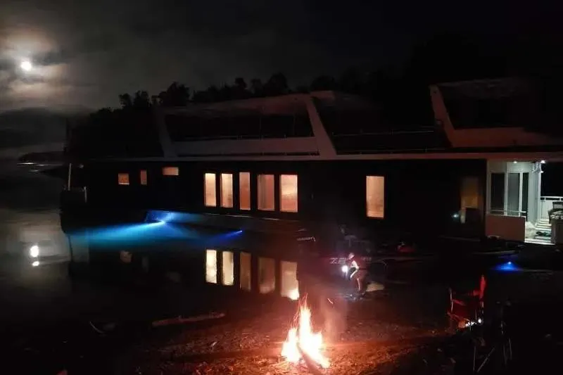 Slide: The Image of Moonlit scene with a 2012 Thoroughbred Houseboat 21x103 and campfire by the water. - 11