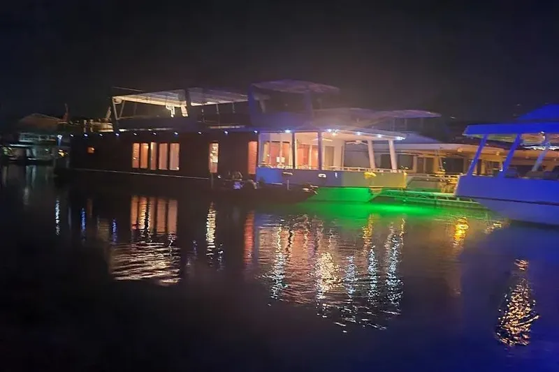 Slide: The Image of Night view of a 2012 Thoroughbred Houseboat 21x103 with colorful lights reflecting on water. - 12