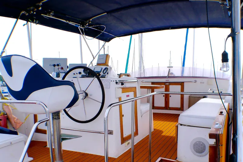 Slide: The Image of 1986 Island Gypsy 40 Motor Yacht helm with seating, wooden deck, and navigation equipment. - 2