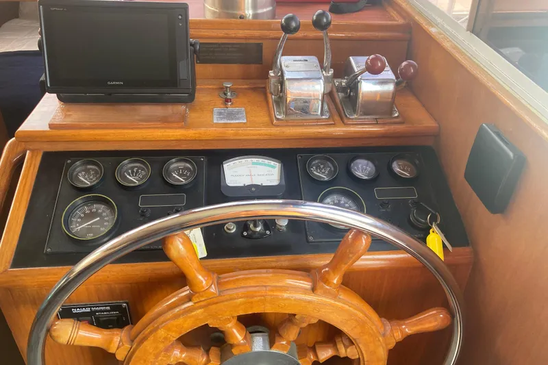 Slide: The Image of 1986 Island Gypsy 40 Motor Yacht helm with wooden wheel, gauges, and navigation equipment. - 22