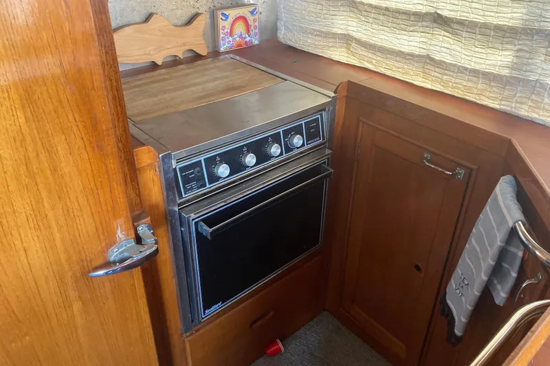Slide: The Image of 1986 Island Gypsy 40 Motor Yacht kitchen with vintage stove and wooden cabinetry. - 27
