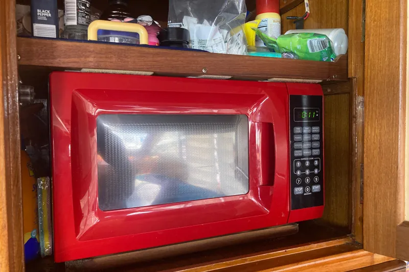 Slide: The Image of Red microwave in wooden cabinet on 1986 Island Gypsy 40 Motor Yacht. - 31
