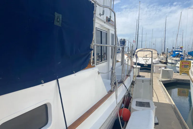 Slide: The Image of 1986 Island Gypsy 40 Motor Yacht docked at marina with blue cover. - 4