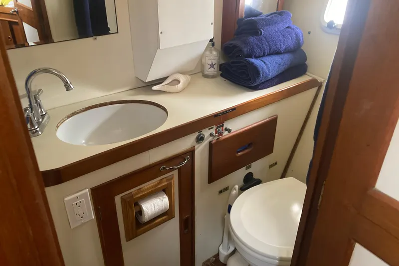 Slide: The Image of 1986 Island Gypsy 40 Motor Yacht bathroom with sink, toilet, and blue towels. - 43