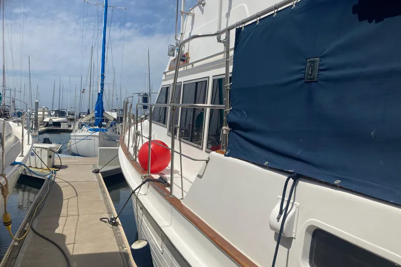 Slide: The Image of 1986 Island Gypsy 40 Motor Yacht docked at marina with blue cover and red buoy. - 5