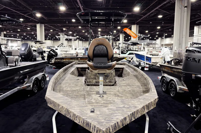 Slide: The Image of 2026 Excel 220 Bay Pro Elite boat displayed at indoor exhibition, surrounded by other boats. - 15