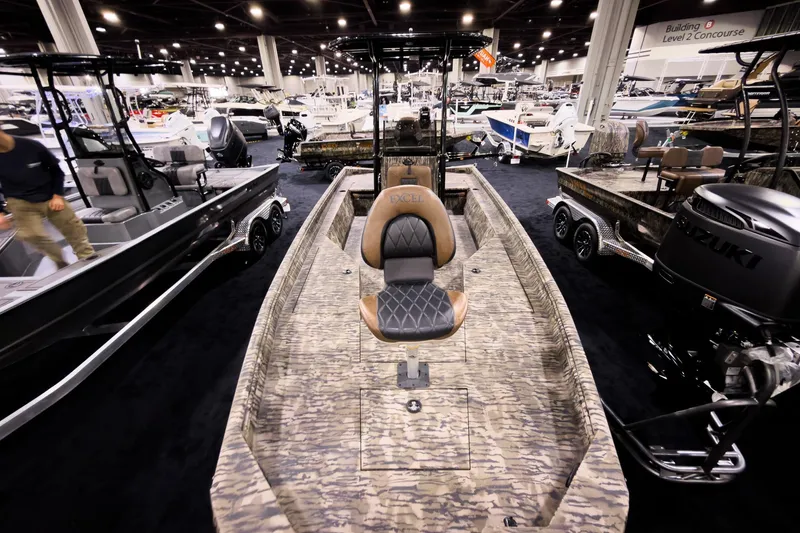 Slide: The Image of 2026 Excel 220 Bay Pro Elite boat displayed at indoor exhibition, featuring camo design and Suzuki engine. - 16