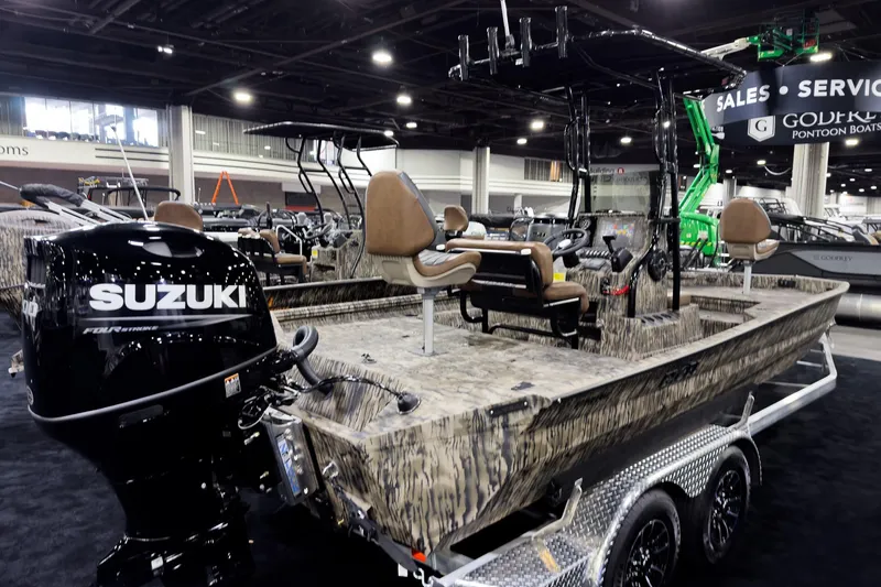 Slide: The Image of 2026 Excel 220 Bay Pro Elite boat with Suzuki engine on display at a boat show. - 2