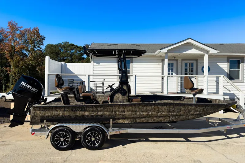 Slide: The Image of 2026 Excel Bay Pro Elite 220 boat on trailer, parked outside a white building. - 24
