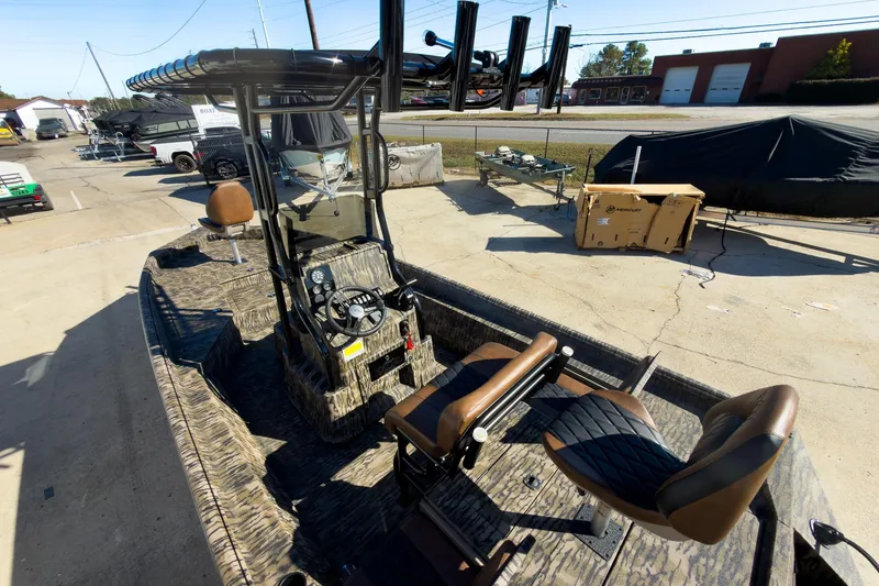 Slide: The Image of 2026 Excel Bay Pro Elite 220 boat with camouflage design and seating, parked outdoors. - 38