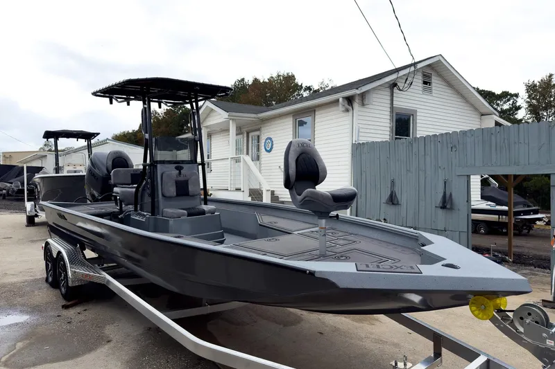 Slide: The Image of 2026 Excel Bay Pro Elite 230 boat on trailer, parked near a white building. - 14