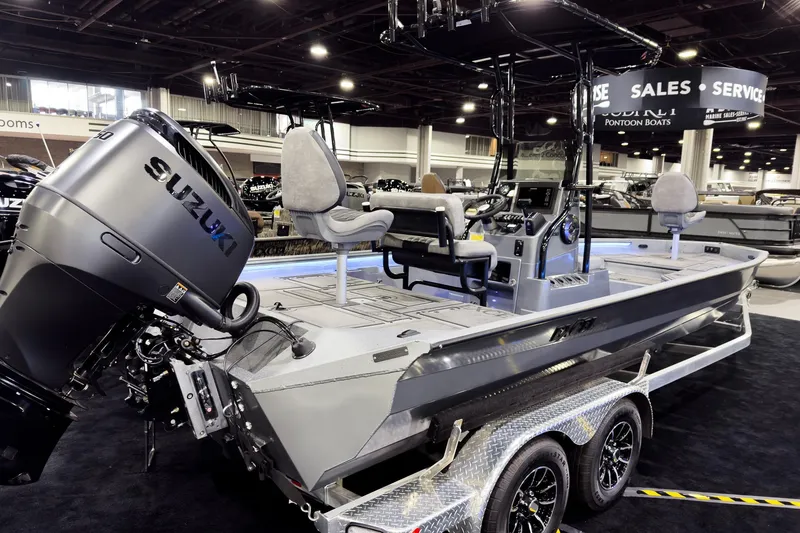 Slide: The Image of 2026 Excel 230 Bay Pro Elite boat with Suzuki engine at indoor showroom display. - 2