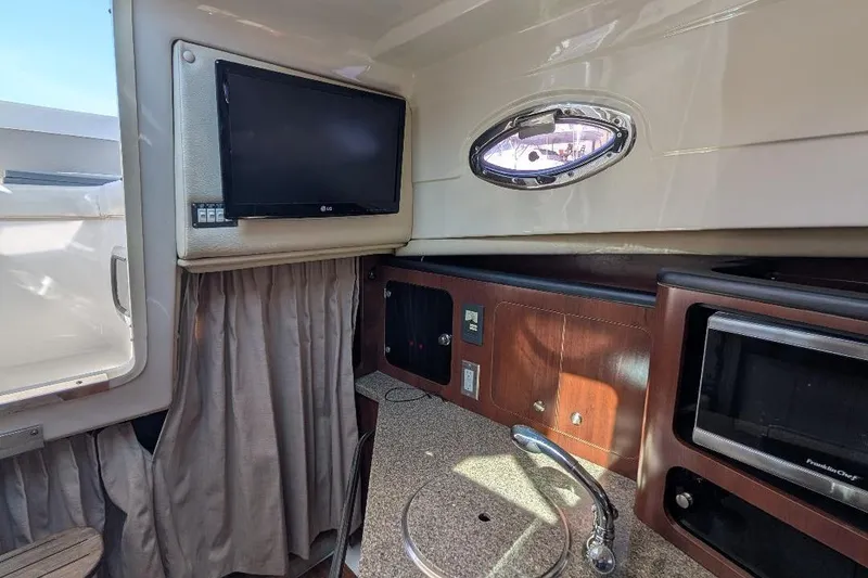 Slide: The Image of 2014 Robalo R305 Walkaround cabin interior with TV, sink, and microwave. - 26
