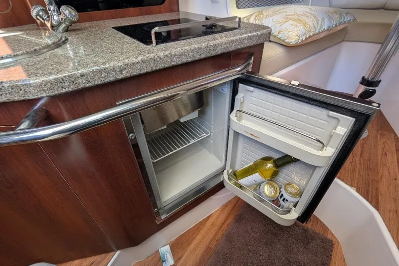 Slide: The Image of 2014 Robalo R305 Walkaround cabin with open mini fridge, wine, and drinks. - 27