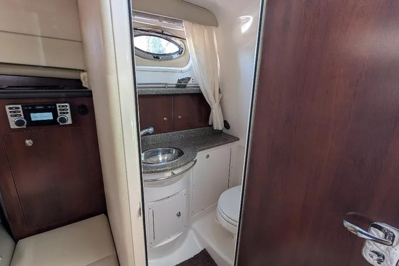 Slide: The Image of 2014 Robalo R305 Walkaround boat interior with sink, toilet, and wooden cabinetry. - 29