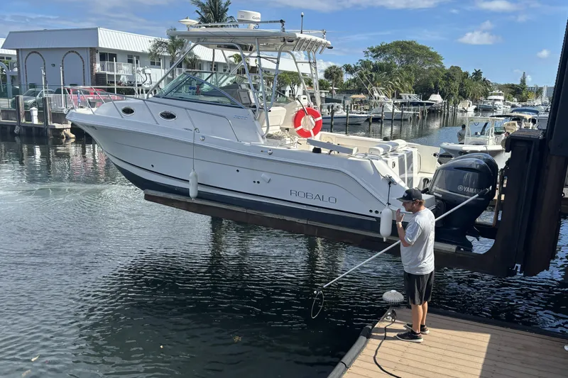 Slide: The Image of 2014 Robalo R305 Walkaround boat being launched at a marina dock. - 8