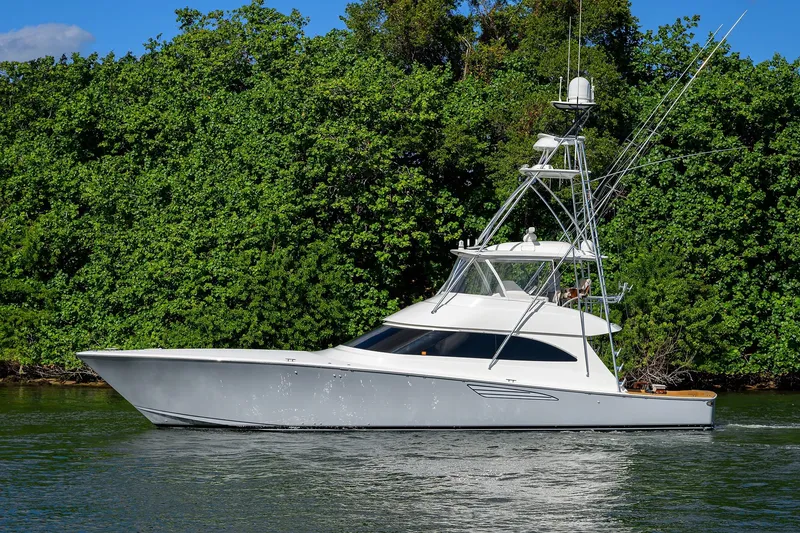 Slide: The Image of 2015 Viking 62 Convertible yacht cruising near lush green shoreline. - 2
