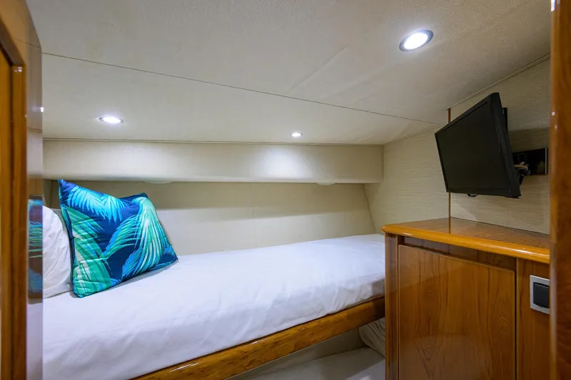 Slide: The Image of 2015 Viking 62 Convertible yacht cabin with bed, TV, and tropical pillow. - 28