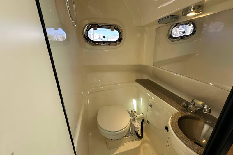 Slide: The Image of 2007 Pursuit OS 285 Offshore boat bathroom with toilet, sink, and porthole windows. - 14