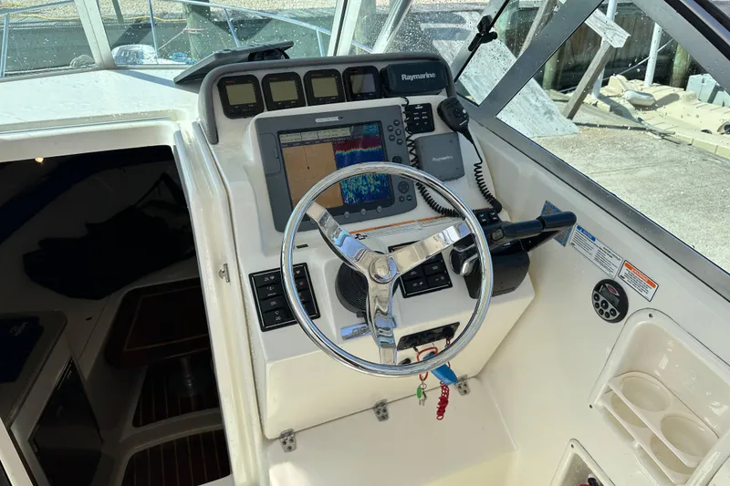 Slide: The Image of 2007 Pursuit OS 285 Offshore boat helm with navigation equipment and steering wheel. - 9
