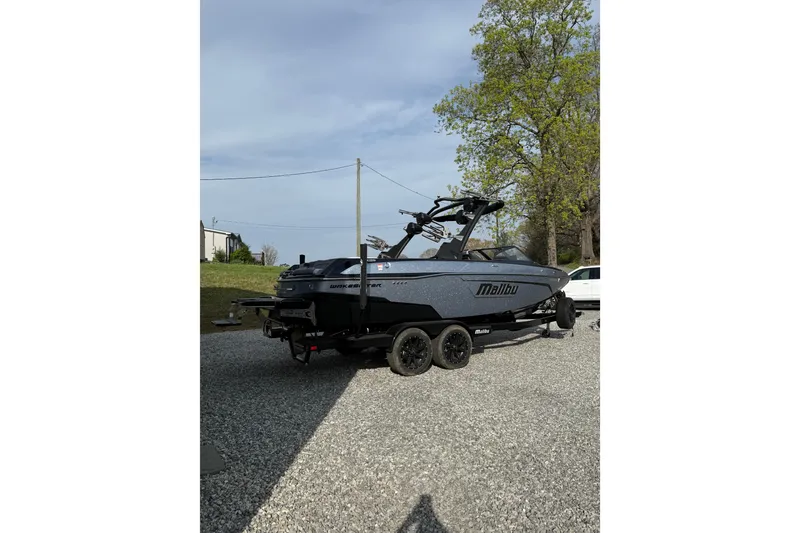 The Image of 2023 Malibu Wakesetter 23 LSV boat on trailer, parked outdoors on gravel. - 1