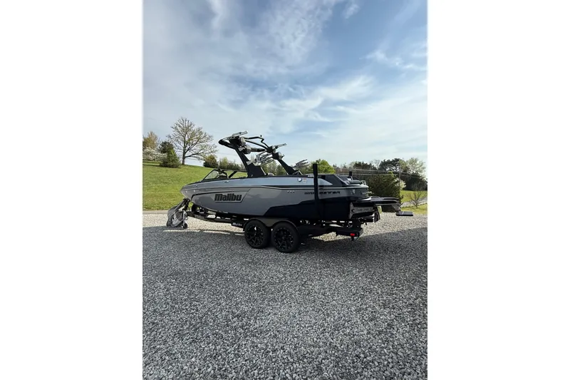 Slide: The Image of 2023 Malibu Wakesetter 23 LSV boat on trailer, parked on gravel with grassy background. - 4