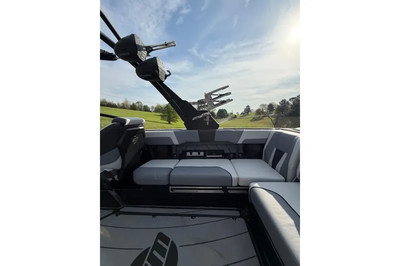 Slide: The Image of 2023 Malibu Wakesetter 23 LSV interior with seating and wakeboard racks under a sunny sky. - 7