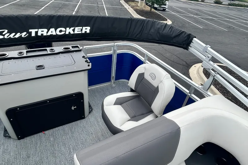 Slide: The Image of 2026 Sun Tracker Fishin' Barge 20 DLX interior with seating and storage in a parking lot. - 14