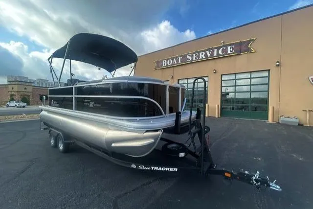 The Image of 2026 Sun Tracker Party Barge 20 DLX pontoon boat parked outside a boat service center. - 0