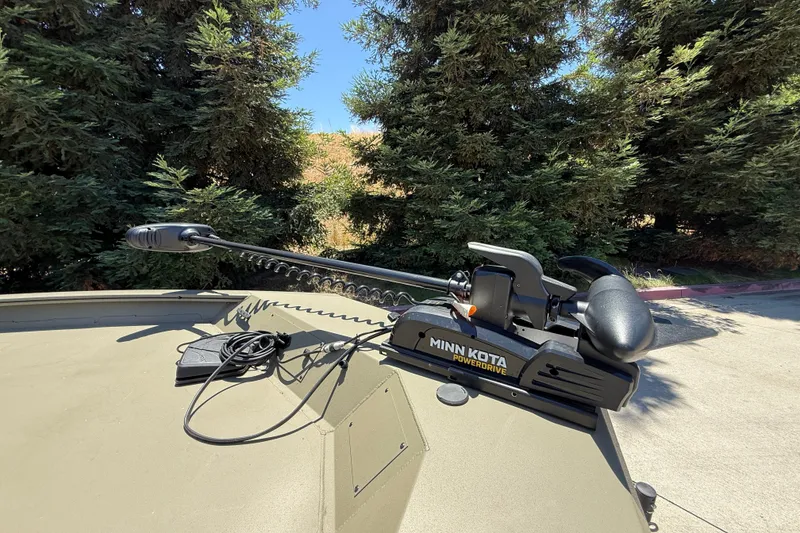 Slide: The Image of Minn Kota PowerDrive motor on 2026 Tracker Grizzly 1860 CC boat, surrounded by trees. - 12