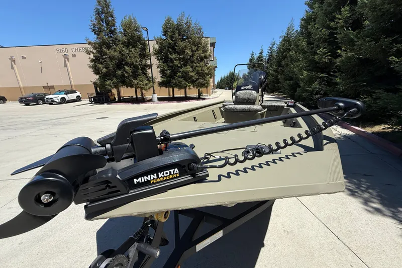 Slide: The Image of 2026 Tracker Grizzly 1860 CC boat with Minn Kota PowerDrive trolling motor in a parking lot. - 13