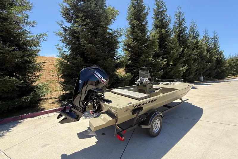 Slide: The Image of 2026 Tracker Grizzly 1860 CC boat with Mercury engine on trailer, surrounded by trees. - 3