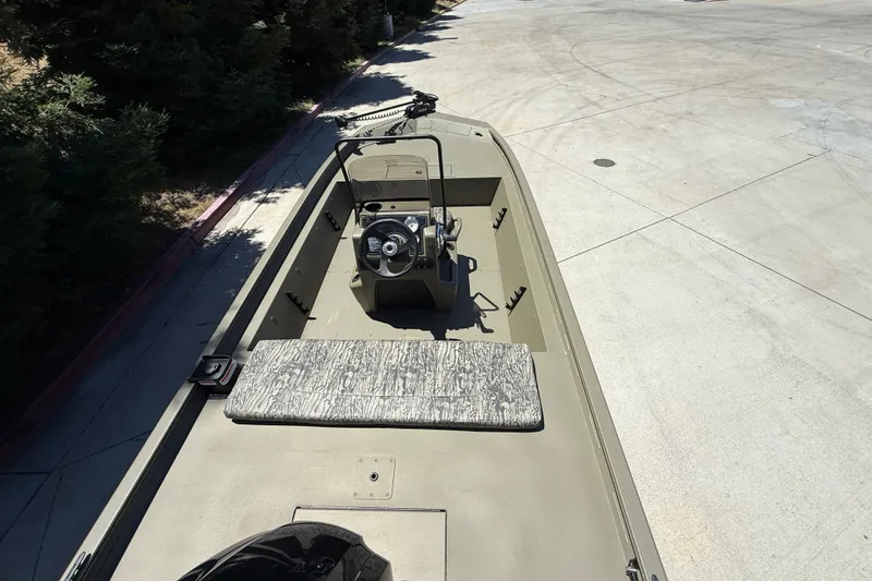 Slide: The Image of 2026 Tracker Grizzly 1860 CC boat on concrete, featuring central console and camouflage seating. - 6