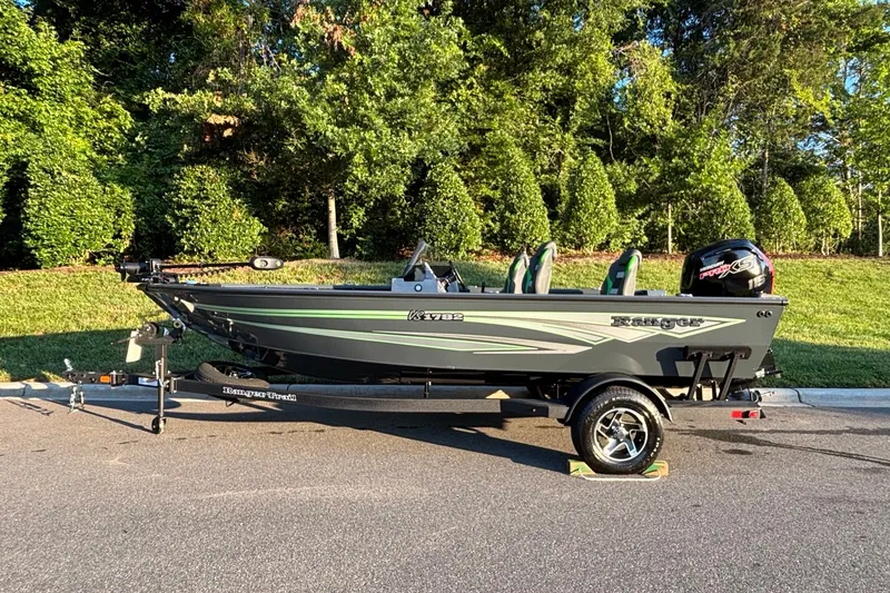 The Image of 2026 Ranger VS1782SC Angler boat on trailer, parked on a sunny road with lush greenery. - 0