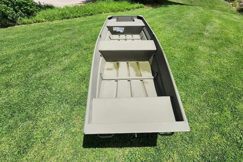 Slide: The Image of 2026 Tracker Grizzly 14 Jon boat on lush green grass, showcasing its spacious interior. - 4