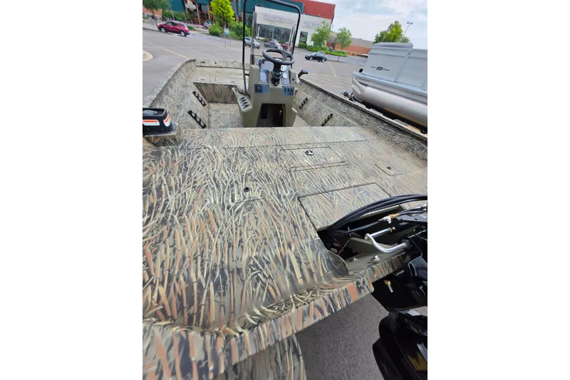 Slide: The Image of 2026 Tracker Grizzly 2072 CC boat with camouflage design in a parking lot. - 2