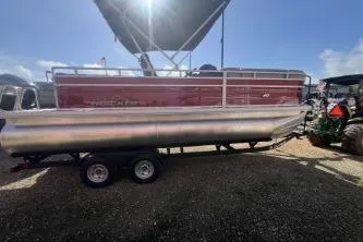 Slide: The Image of 2026 Sun Tracker SportFish 20 DLX pontoon boat on trailer under sunny sky. - 2