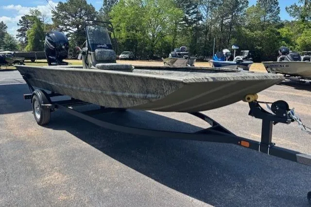 Slide: The Image of 2026 Tracker Grizzly 1860 CC boat on trailer, parked outdoors with trees in background. - 5